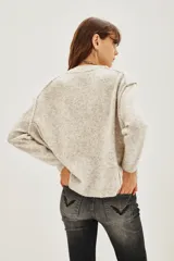 Sweater amarillo de calce relajado, mangas largas, cuello redondo y hombros caídos.