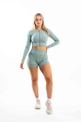 Conjunto deportivo color verde agua, compuesto por un top corto con cierre frontal y calzas cortas.