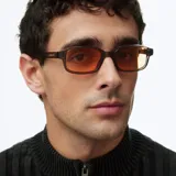 Lentes de sol con silueta rectangular, montura gruesa color camel y cristales naranjas.