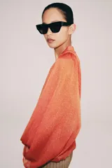 Top de punto color naranja con cuello polo, escote en V y mangas largas amplias con bajo abullonado.