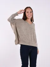 Buzo de tejido de punto fino color gris melange, con escote en V, mangas largas con detalle de volado en los hombros y corte holgado.