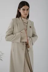 Tapado largo de paño en color beige, con solapas clásicas, cierre frontal de dos botones y corte recto estructurado.