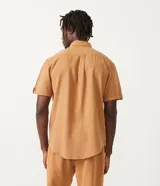 Camisa de hombre de manga corta color marrón, confeccionada en lino y algodón. Presenta cuello clásico, botonadura frontal, bolsillo en el pecho y mangas con botón para enrollar.