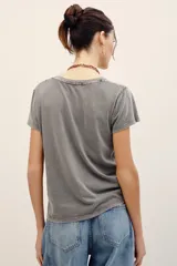 Remera de algodón gris con efecto acid wash, mangas cortas y estampa frontal de labios oscuros con la palabra "Kiss" en rojo.