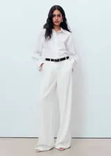 Camisa de corte recto y diseño crop, confeccionada en tejido popelín. Presenta cuello camisero clásico, cierre delantero con botones ocultos y mangas largas con puños abotonados.