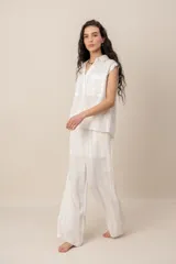 Conjunto compuesto por una blusa sin mangas con cuello camisero, bolsillos frontales y cierre de botones, y un pantalón largo de corte recto y holgado, ambos confeccionados en tejido texturizado de color marrón.