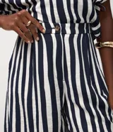 Short femenino de viscosa y poliamida, con estampado de rayas verticales blancas y azul marino. Presenta un modelo corto, cintura elástica y cierre de botón.