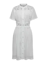 Vestido midi blanco de lino orgánico y viscosa, con cuello mao, mangas cortas y cierre frontal de botones. Presenta detalles de encaje en los hombros, el pecho y la cintura.