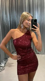 Vestido corto de fiesta confeccionado en tela con lentejuelas bordadas, de diseño ajustado al cuerpo con escote asimétrico de un solo hombro.