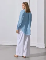 Camisa celeste de tencel, marca Hester & Orchand. Tiene cuello con solapa, escote en V, abertura central con botones, bolsillo aplicado en el frente y ruedo desflecado.