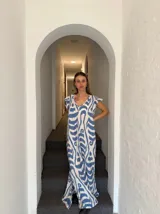 Vestido largo color blanco con estampado abstracto en azul, escote en V y mangas cortas.