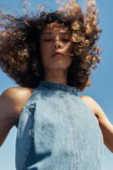 Vestido corto de denim con cuello halter, espalda descubierta y diseño de lavado combinado en tonos de azul.