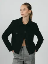 Chaqueta corta negra con cuello clásico, cierre frontal con botones, bolsillos de parche en el pecho y forro interior.