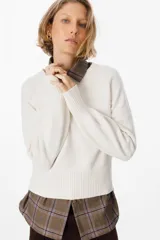 Sweater de silueta holgada en color crudo, con cuello redondo, mangas largas y puños anchos acanalados.