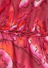 Vestido maxi de algodón con diseño estampado en tonos fucsia y naranja. Presenta escote en pico, tirantes finos dobles y espalda descubierta con cierre de lazo. Diseño evasé sin mangas.