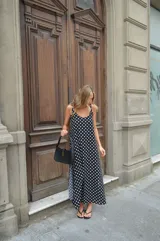 Vestido largo de crepe con estampado de lunares negros sobre fondo blanco. Presenta un diseño de corte holgado con breteles finos y escote redondeado.