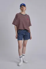 Remera oversize a rayas horizontales en tonos bordó y blanco, con cuello redondo verde oscuro y un pequeño parche bordado en forma de corazón en el pecho.