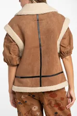 Chaleco estilo gamulán de color negro, con interior y cuello de corderito sintético. Presenta cierre frontal, detalles en cuero sintético y corte oversize.