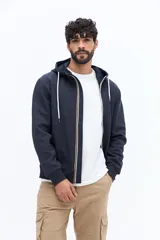 Campera de felpa azul marino con cierre frontal, capucha ajustable con cordones blancos y bolsillos canguro. Presenta un pequeño parche estampado en el pecho izquierdo.