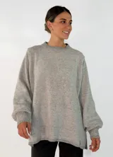 Sweater de tejido de punto color gris melange, con cuello redondo, mangas largas con puños ajustados y diseño holgado con aberturas laterales en el ruedo.
