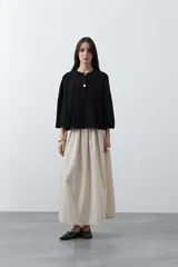 Saco tipo capa de punto color negro, con silueta fluida, corte amplio y cierre frontal con dos botones dorados.