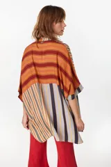 Vestido camisero corto con diseño de paneles combinados en distintos patrones de rayas verticales y horizontales, en tonos rojo, azul, beige y blanco. Posee cuello mao, cierre frontal con botones y mangas cortas caídas.