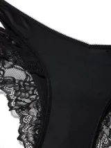 Braguita cheeky negra de talle bajo, confeccionada en suave microfibra con diseño de cortes laterales y detalles de encaje floral elástico. Presenta tiro en V y corte de pierna alto.