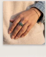Anillo de plata envejecida con diseño ancho y tres piedras naturales verdes ovaladas dispuestas en línea.