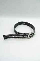 Cinturón de diseño trenzado en color negro con hilos plateados entrelazados, presenta una hebilla metálica ovalada de acabado brillante.