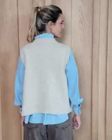 Chaleco de punto con diseño de trenzas, color gris oscuro, con cierre frontal de botones grandes y bolsillos laterales.