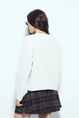 Sweater negro de tejido texturizado con líneas horizontales en relieve, de silueta levemente holgada y hombros caídos.