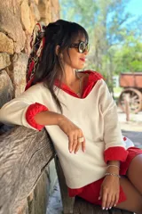 Sweater de tejido de punto fino en color blanco, con cuello en V y mangas largas. Presenta un diseño holgado y versátil, ideal para usar como prenda única o en capas.