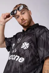 Camiseta de estilo futbolero con cuello polo, manga corta y corte relajado. Presenta un estampado abstracto en tonos grises y negros, con el número 15, el logo de la marca y la palabra Endzone en el frente.