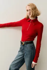 Top de manga larga confeccionado en tejido de punto acanalado. Presenta un diseño de ajuste ceñido con cuello alto y cierre frontal parcial.