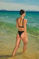 Conjunto de bikini negro de lycra texturada, compuesto por un corpiño triangular fijo con elástico interno bajo el busto y una bombacha vedetina con elástico interno.