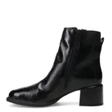 Bota de caña media confeccionada en cuero negro con acabado brillante. Presenta un taco cuadrado de altura media, puntera redondeada y detalle de hebilla metálica lateral con elástico para un mejor ajuste.