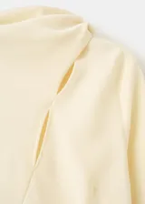 Blusa de manga larga color amarillo claro, con cuello alzado y detalle de abertura asimétrica en el escote.