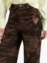 Pantalón de corderoy de algodón con silueta wide leg y tiro alto. Presenta un diseño de estampado camuflado con detalles de corazones bordados distribuidos en la prenda.