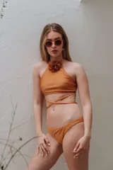Conjunto de bikini color tostado con corpiño halter que incluye un aplique de flor de tela en el cuello y tiras cruzadas en la cintura, combinado con bombacha vedetina clásica.