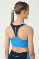 Top deportivo azul y celeste con costuras en verde, espalda cruzada y logo retro de Basset.