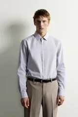 Camisa de corte slim fit con estampado de rayas verticales finas, cuello italiano, manga larga con puños abotonados y cierre frontal de botones.