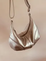 Cartera plateada tipo banana bag de cuero, con correa ajustable y cierre superior.