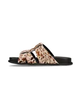 Sandalias planas de cuero con estampa animal print tipo vaca, con tiras cruzadas y suela negra.