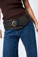 Cinturón ancho negro con hebilla metálica y múltiples tachas doradas envejecidas.