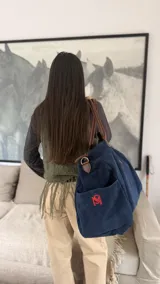 Bolso de mano tipo duffel color azul marino, de gran capacidad, con asas de cuero marrón y correa ajustable para hombro o cruzada.