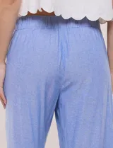Pantalón crop de lino y rayón, con diseño wide leg de corte holgado, estampado tropical de hojas en tonos verde, azul y marrón sobre fondo blanco. Cuenta con pretina trasera elastizada y bolsillos delanteros.