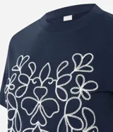 Remera de algodón color azul marino, con cuello redondo, mangas cortas y un bordado frontal en color blanco con diseño simétrico de motivos florales.