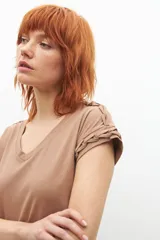 Remera negra de corte recto, con cuello en V y detalle de trenzas en los hombros.