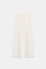 Pantalón fluido de tiro medio, color blanco, con cintura elástica ajustable con cordones, bolsillos laterales y bajo ajustable con trabilla y botón a presión.