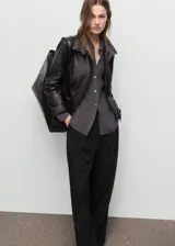 Pantalón de vestir negro de tiro medio con diseño wide leg, detalle de pinzas frontales, bolsillos laterales y cierre delantero con botón, gancho y cremallera ocultos.